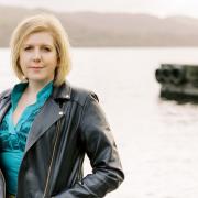 Author Clare Mackintosh standing by a lake.