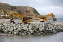 Jones Bros placing some of the 70,000 tonnes of North Wales sourced rock armour coastal defence into place at Penrhyn Bay.