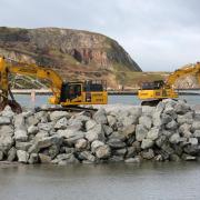 Jones Bros placing some of the 70,000 tonnes of North Wales sourced rock armour coastal defence into place at Penrhyn Bay.